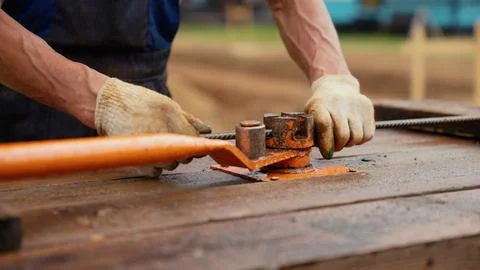 Construction worker hands bending metal rebar with tool Stock Photos