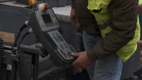 Construction worker hands operating electronic control panel on asphalt pav.. Video stock 339802515