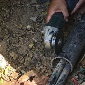 Construction worker hands using angle grinder power tool. Stock Photos