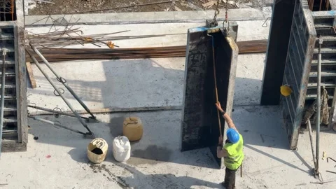 A construction worker in a hard hat applies release oil to the inner surface of Stock Footage 332653705