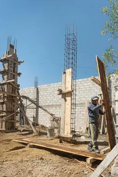 Construction worker in hardhat holding up plank at site Stock Photos