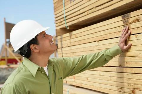 Construction Worker In Hardhat Inspecting Lumber Stock Photos