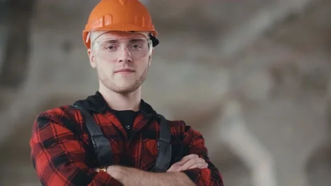 Construction worker in a helmet and overalls. Portrait, close-up looking at the Video stock 130775502
