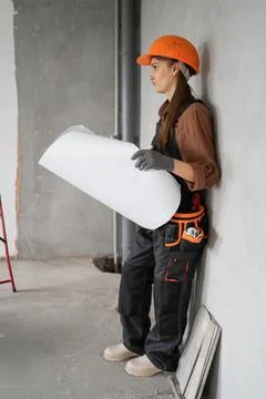Construction worker in helmet and overalls reading blueprints of new house .. Stock Photos