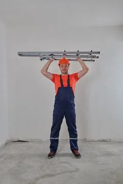 A construction worker in a helmet holds a stepladder Stock Photos