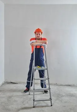 A construction worker in a helmet leaned on a stepladder Stock Photos