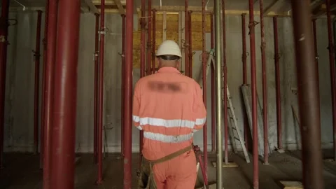Construction worker in high-visibility gear walking through the space Stock Footage 299134826