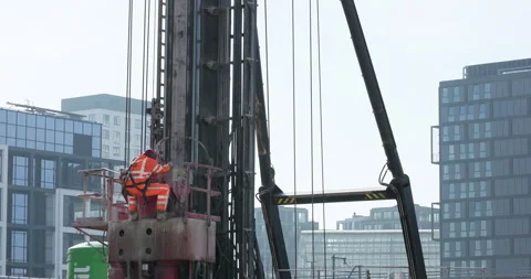A construction worker in high-visibility gear operating heavy drilling equipment Stock Footage 303523082