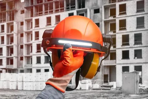 Construction worker in a high-visibility vest holding an orange safety helm.. Stock Photos