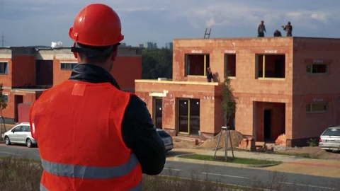 A construction worker (his back to the camera) looks around a site - a house Stock-Footage 81204246