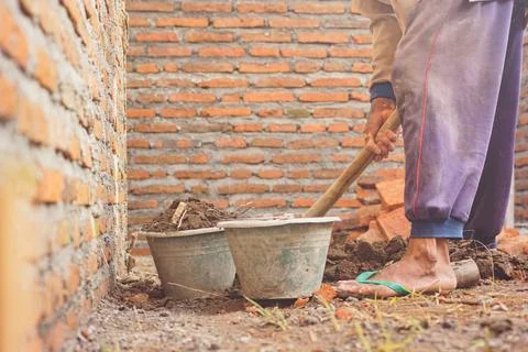 Construction worker hoeing to level the house building Stock Photos
