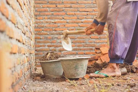 Construction worker hoeing to level the house building Stock Photos