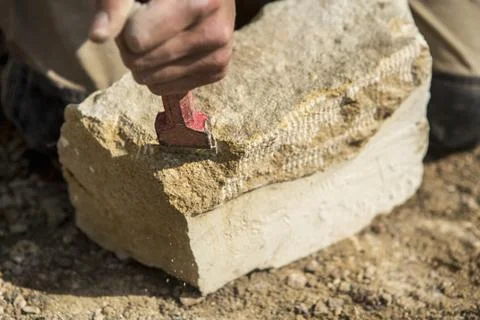Construction worker holding a chisel, working on stone. Stock Photos