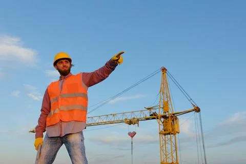 Construction worker holding level tool at building site with crane Stock Photos