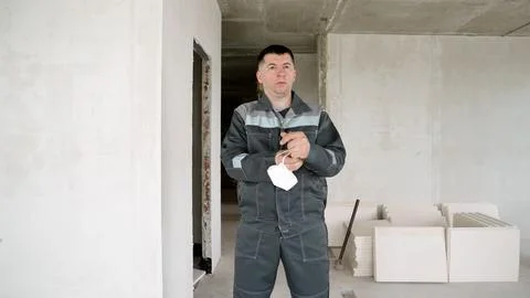 Construction worker holding protective mask in unfinished building interior Fotos Stock