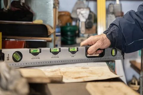 A construction worker holding a spirit level tool on a flat surface to check Stock Photos