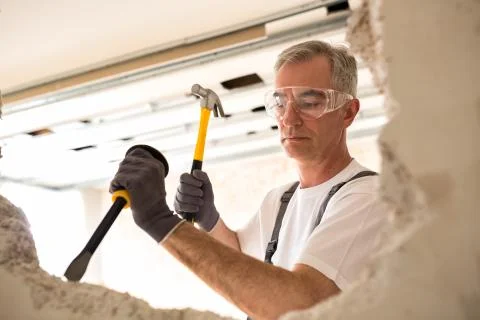 Construction worker holding tool and smash drywall Foto stock