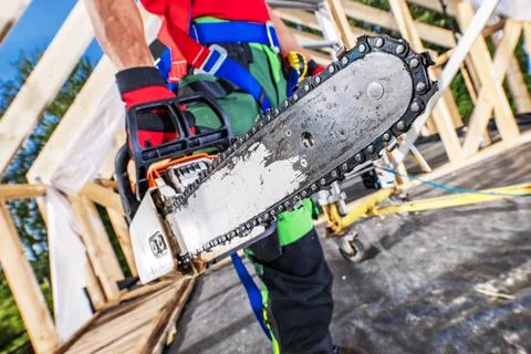 Construction worker holds chainsaw on a building site in daylight hours Stock Photos