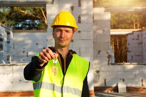 Construction worker holds out key to the house. Turnkey construction, relocat Foto stock
