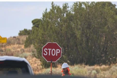 A construction worker holds a red stop sign to control traffic Foto stock