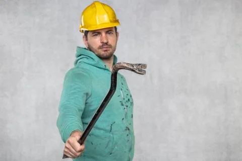 The construction worker holds a work tool in his hands, a crowbar Stock Photos