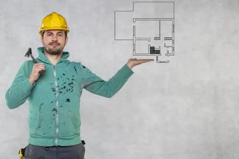 The construction worker holds a work tool in his hands, a crowbar, plans of a Stock Photos