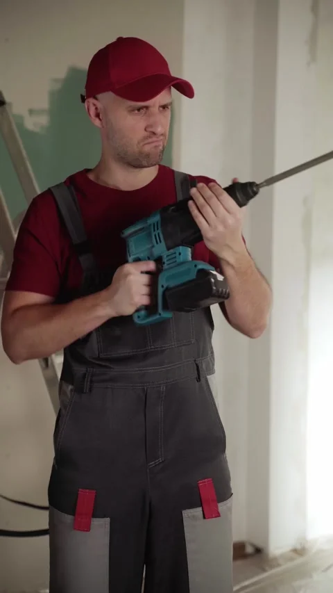 Construction worker inspecting rotary hammer drill during renovation work 스톡 동영상 311928037