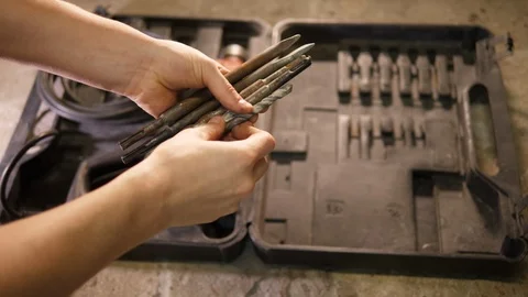 Construction worker inspecting variety big old rusty Drill bit tools. Handyman. Stockbeeldmateriaal 126341897