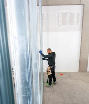 Construction worker installing aluminum studs for drywalling a new wall Stock Photos