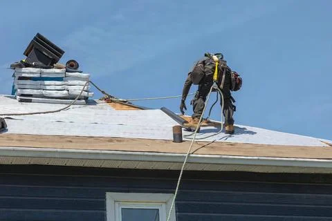 Construction Worker Installing Asphalt Shingles on House Roof Stock Photos