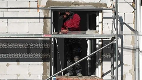 Construction worker installing insulation on a building facade with scaffolding. Stock Footage 338157054