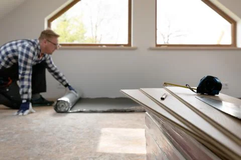 Construction worker installing laminate floor in a new renovated attic. Home Stock Photos