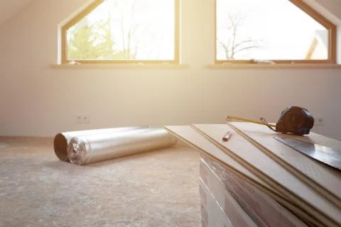 Construction worker installing laminate floor in a new renovated attic. Home Stock Photos