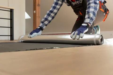 Construction worker installing laminate floor in a new renovated attic. Home Stock Photos
