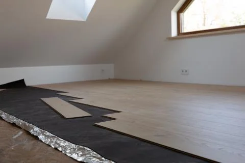 Construction worker installing laminate floor in a new renovated attic. Home Stock Photos
