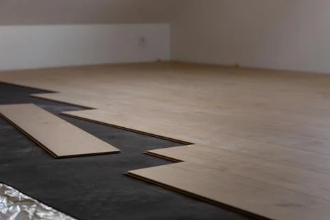 Construction worker installing laminate floor in a new renovated attic. Home Stock Photos