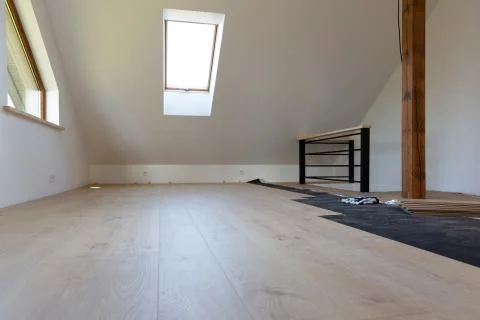 Construction worker installing laminate floor in a new renovated attic. Home Stock Photos