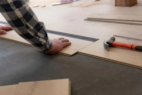 Construction worker installing laminate floor in a new renovated attic. Home Stock Photos