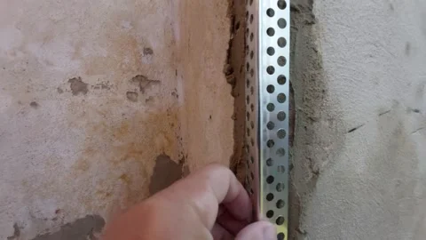 Construction worker installing a metal corner bead profile on an old plaster wal Stock Footage 337054613