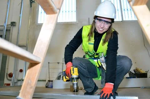 Construction worker installing plasterboard with power drill Stock Photos