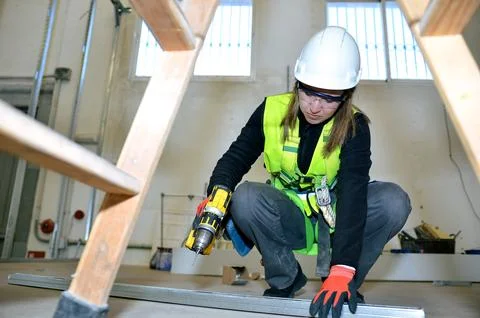 Construction worker installing plasterboard with a power drill Foto stock