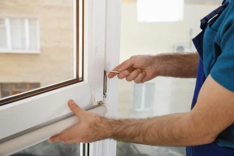 Construction worker installing plastic window in house, closeup Stock Photos