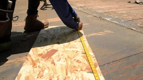 Construction worker installing roofing underlayment on a roof deck using OSB Stock Footage 341784683