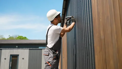 Construction worker installing siding on building exterior Stock Footage 316712797