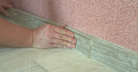 Construction worker installing skirting board on laminate floor Stock Footage 306849441