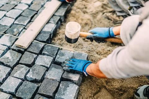 Construction worker installing stone on pavement. Details of construction site Stock Photos