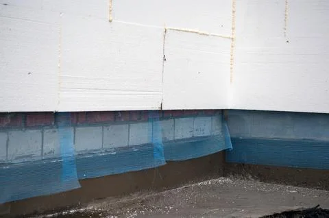 Construction worker installing styrofoam insulation sheets on house facade wa Stock Photos