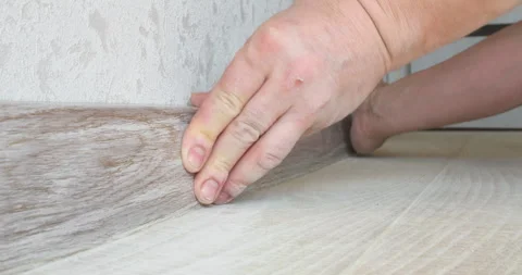 Construction worker installing wooden skirting board on laminate floor Stock Footage 306851983