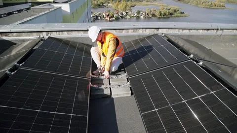 A construction worker installs solar panels on a roof using an electric drill. Vídeo Stock 331518468