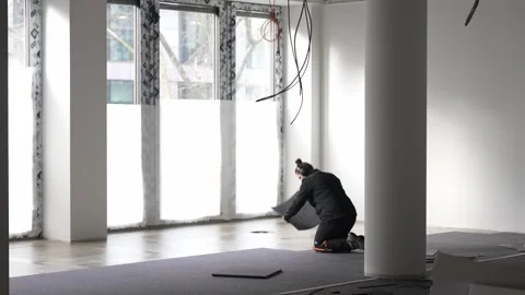 Construction worker kneeling on floor installing panels inside unfinished Stock Footage 332531309
